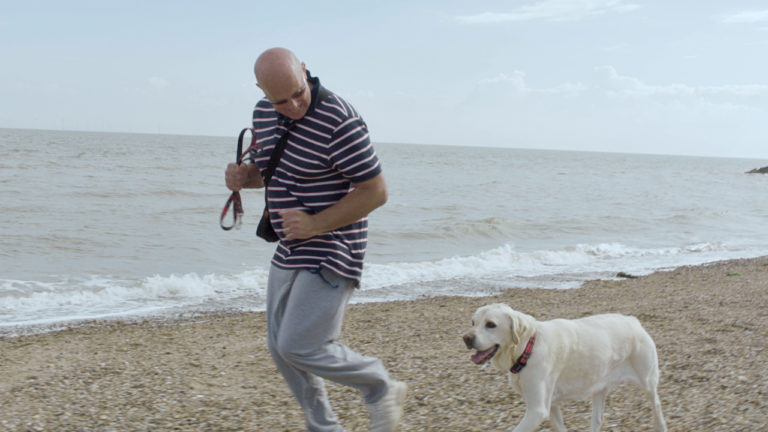 A man walking his dog on a beach