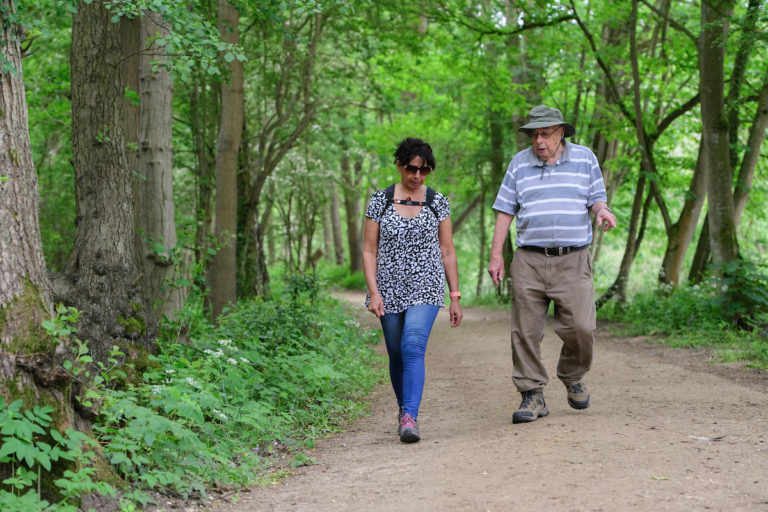 A man and lady walking along a tree lined path