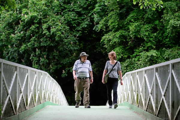 Man and a woman walking over a bridge in a park