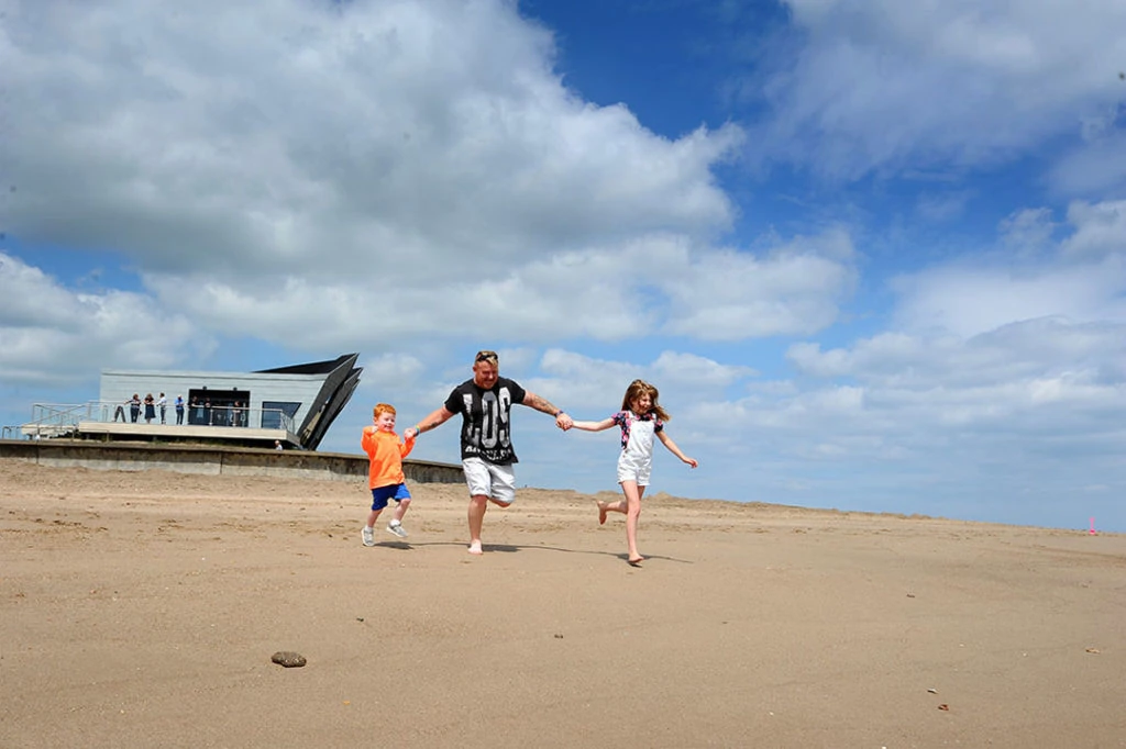 Man with two children running along a beach