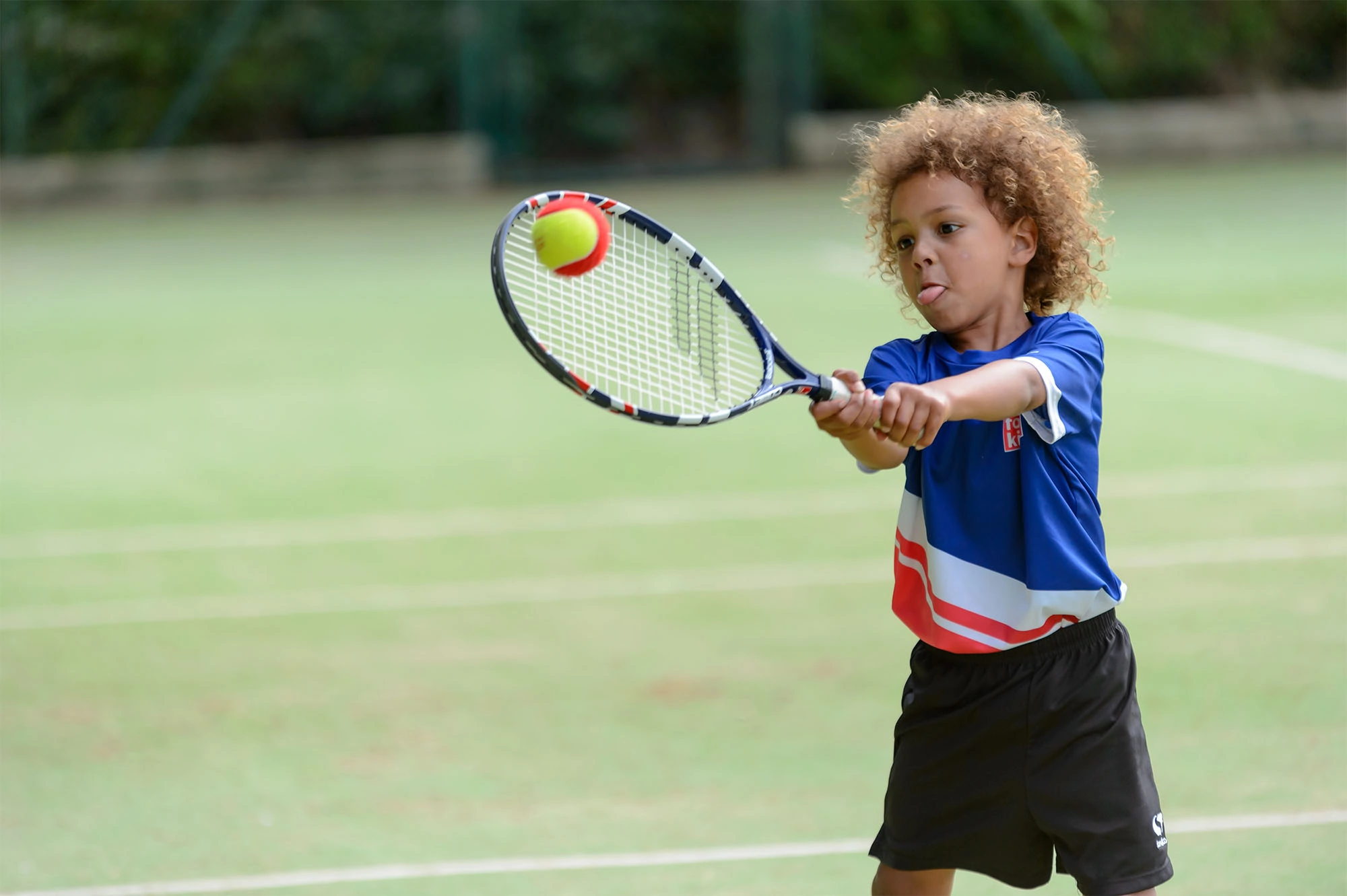 boy hitting a ball with a tennis racket
