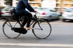 person cycling past cars