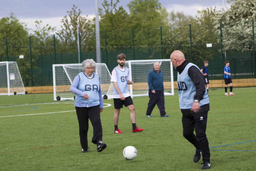 men and women playing walking football on an outside pitch