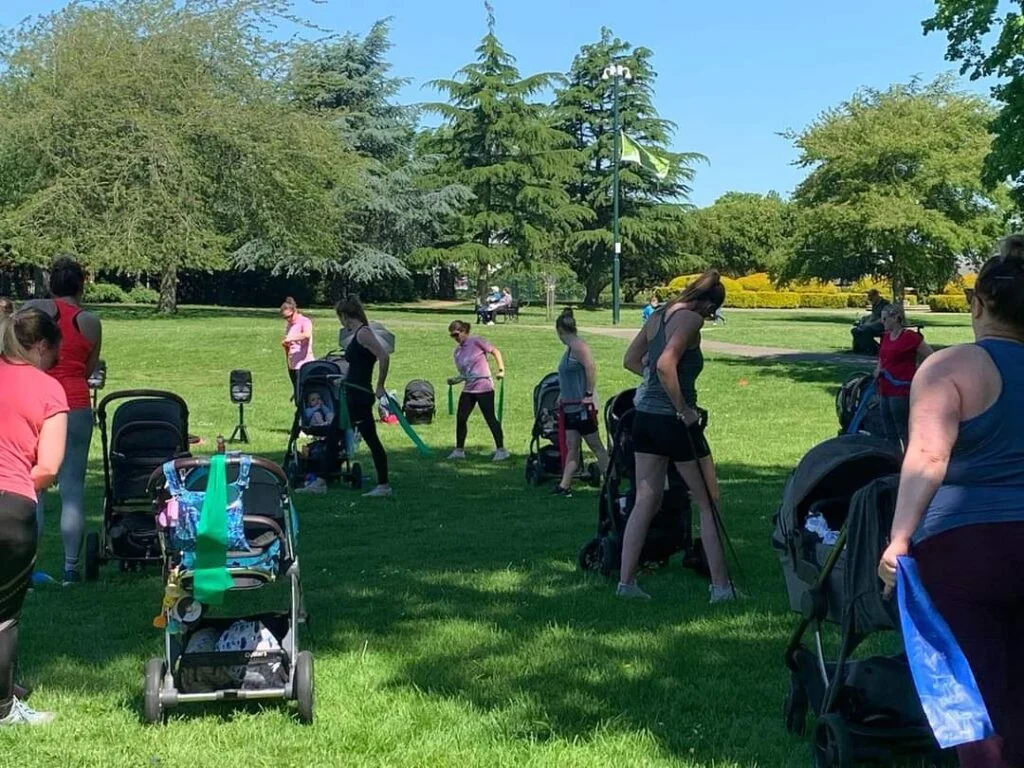 Women with buggies in a park doing exercise.