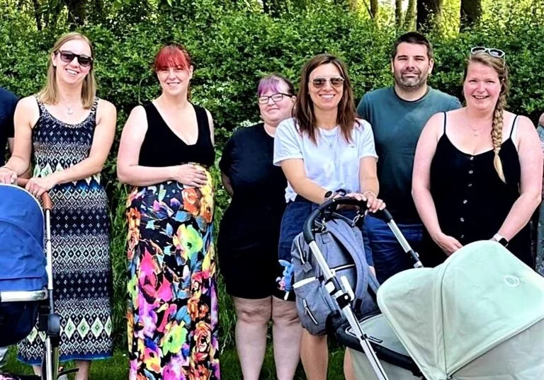 A group of people posing for a photo with two prams.