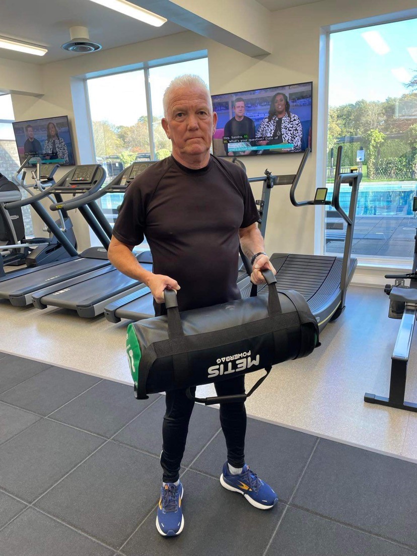 Man in gym clothes holding a fitness slam bag.