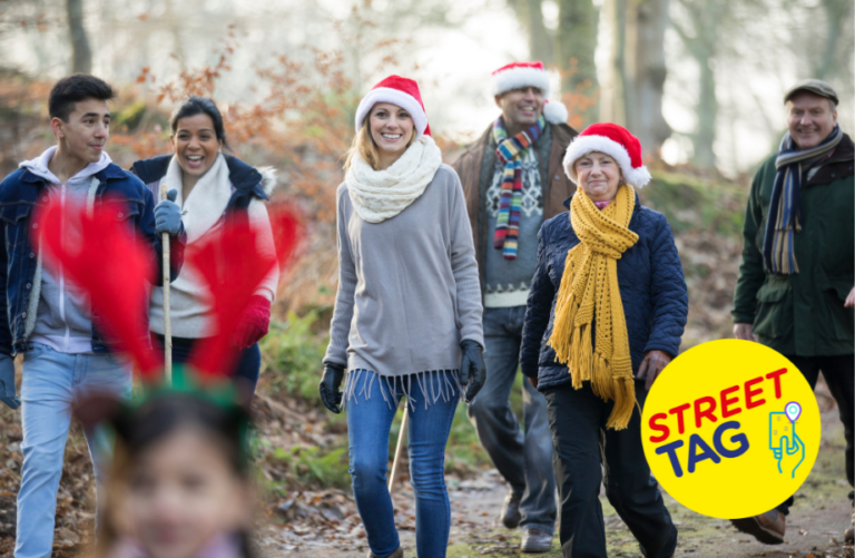 A group of people of different ages go for a walk wearing winter jumpers, scarves and santa hats.