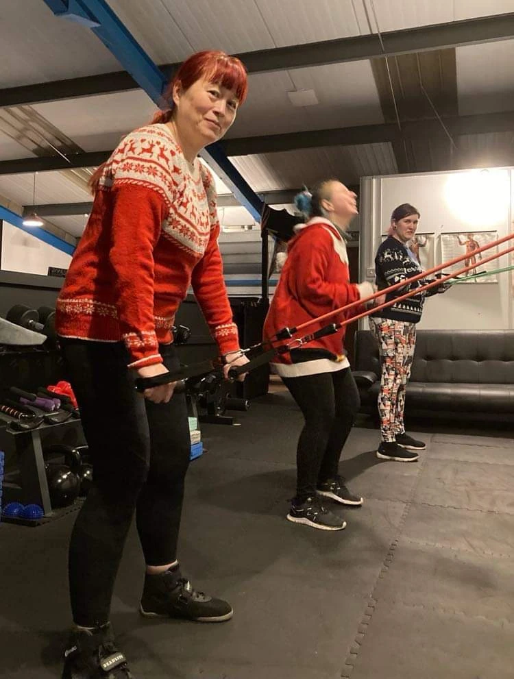 Three women in festive jumpers using the gym equipment at Darkside Rising Gym.