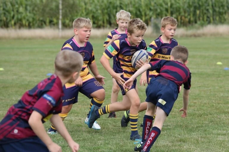 Children playing rugby on a field.