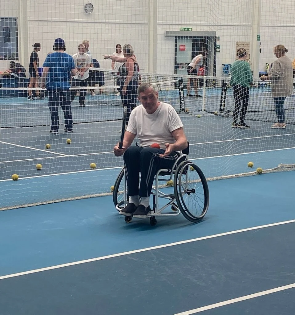 A man in a wheelchair playing tennis.