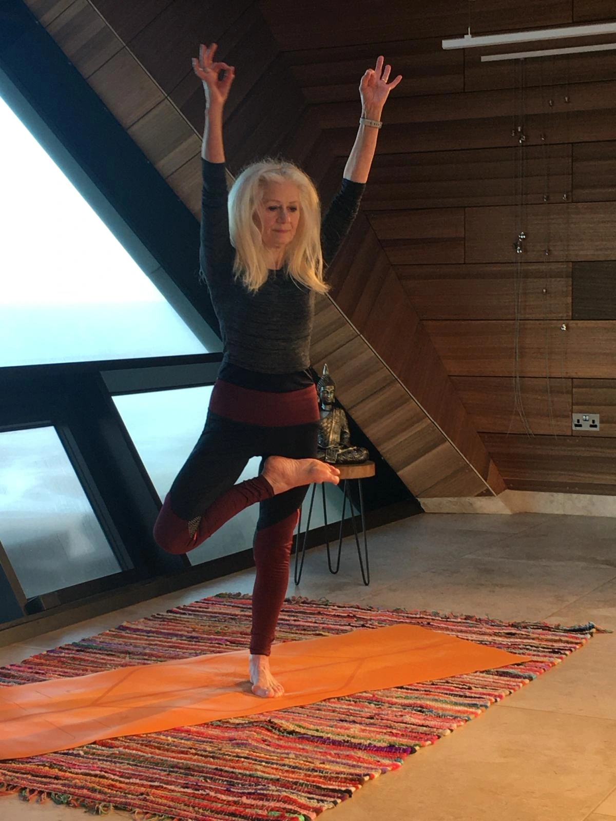 Irene Epsley of East Coast Yoga doing a standing yoga pose on a rug in front of a window at the North Sea Observatory