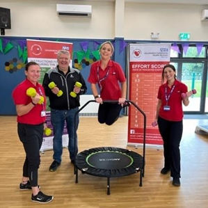 Members of staff from cardiac rehab pose for a photo with mini trampoline and hand weights
