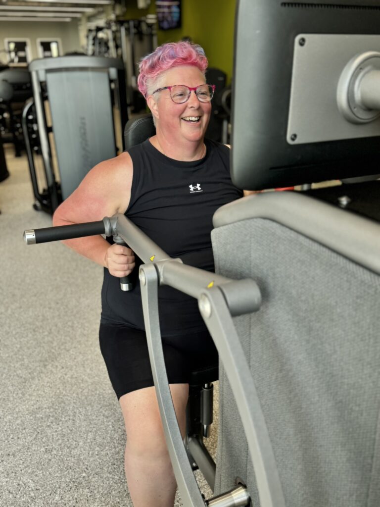 A lady smiles as she works out in the gym.