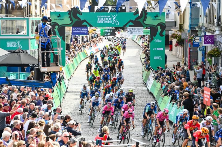 A cycle race through a street packed with crowds onlooking